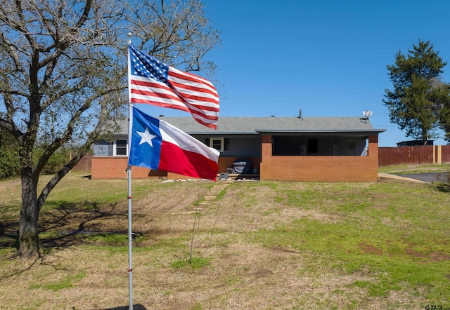 rear view of house with a lawn and fence