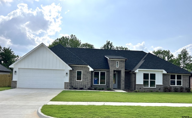 view of front of property with a front yard, driveway, a garage, and brick siding