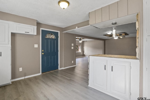 foyer entrance with ceiling fan, a textured ceiling, and light wood-type flooring