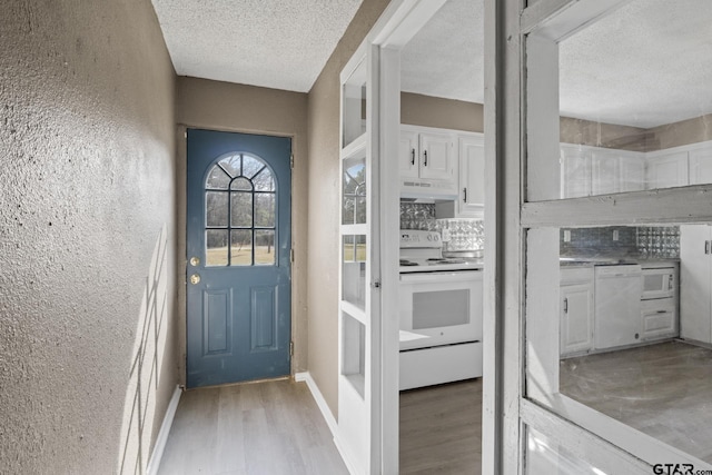 doorway to outside featuring a textured ceiling and light wood-type flooring