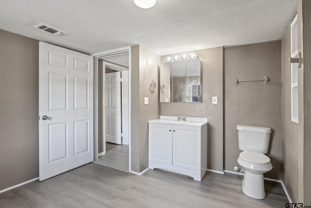 bathroom featuring vanity, toilet, hardwood / wood-style floors, and a textured ceiling