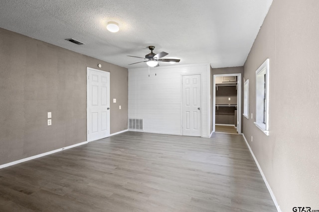 empty room with hardwood / wood-style floors, a textured ceiling, and ceiling fan