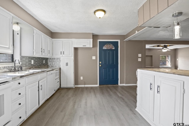 kitchen featuring pendant lighting, light hardwood / wood-style flooring, stove, white cabinets, and decorative backsplash