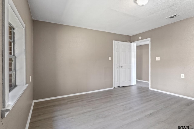 empty room featuring light hardwood / wood-style flooring and a textured ceiling