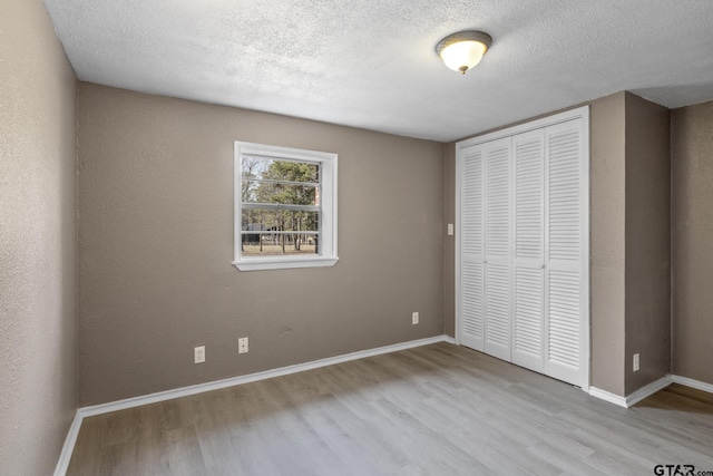 unfurnished bedroom featuring a closet, a textured ceiling, and light wood-type flooring