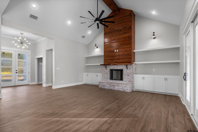 unfurnished living room featuring a brick fireplace, beam ceiling, wood-type flooring, built in features, and ceiling fan with notable chandelier