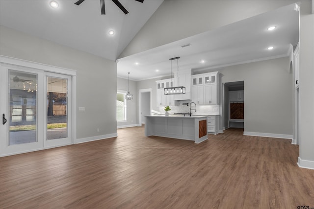 kitchen featuring white cabinetry, a kitchen island with sink, ornamental molding, dark hardwood / wood-style floors, and pendant lighting