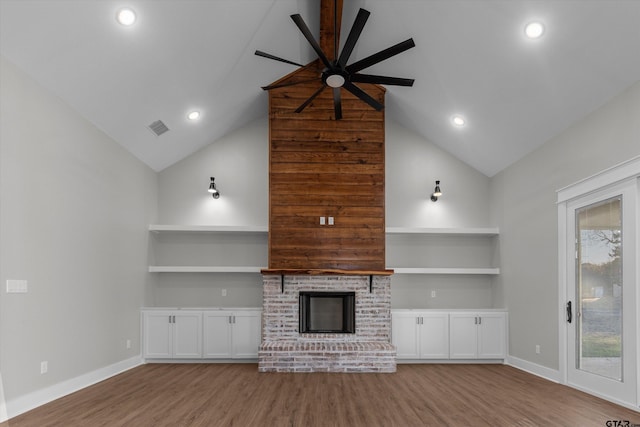 unfurnished living room with a fireplace, built in shelves, ceiling fan, and light hardwood / wood-style flooring