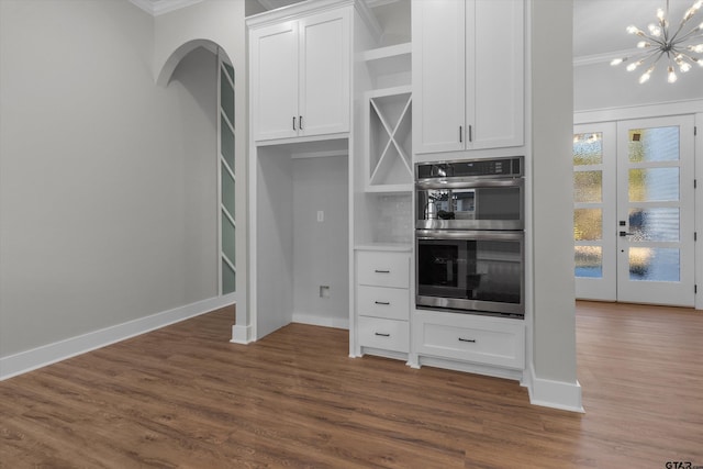 kitchen with dark wood-type flooring, white cabinets, crown molding, and double oven