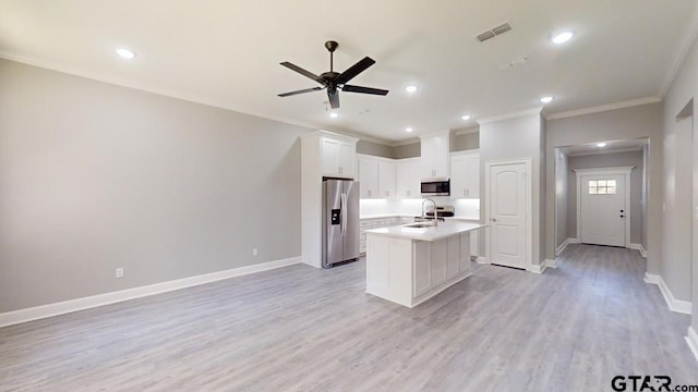 kitchen with white cabinetry, appliances with stainless steel finishes, ornamental molding, an island with sink, and light hardwood / wood-style flooring