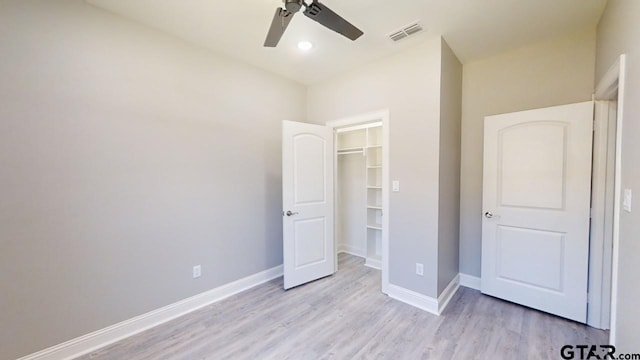 unfurnished bedroom with a closet, a spacious closet, ceiling fan, and light hardwood / wood-style flooring