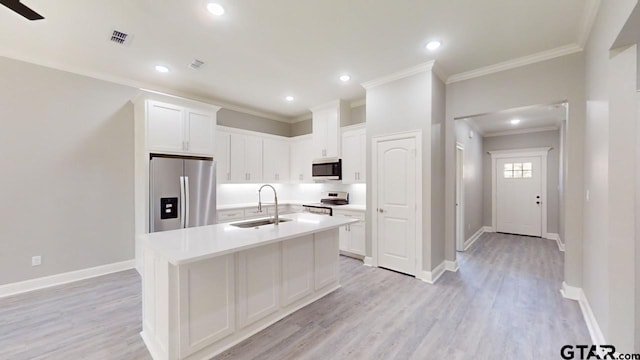 kitchen with light hardwood / wood-style floors, stainless steel appliances, sink, an island with sink, and white cabinetry