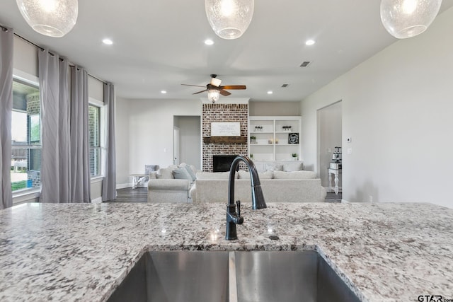 261 Heritage Way, Bullard, TX 75757 - kitchen featuring ceiling fan, a sink, light stone counters, a brick fireplace, and recessed lighting
