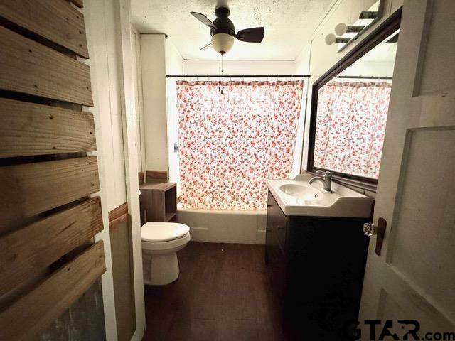 full bathroom with vanity, toilet, shower / bath combo with shower curtain, a textured ceiling, and wood-type flooring