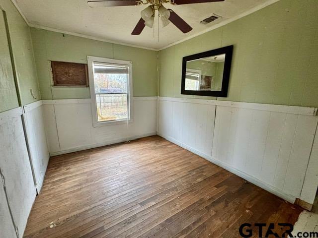 spare room featuring hardwood / wood-style flooring, ceiling fan, and ornamental molding