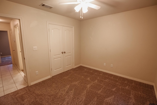 unfurnished bedroom with ceiling fan, a closet, and dark carpet