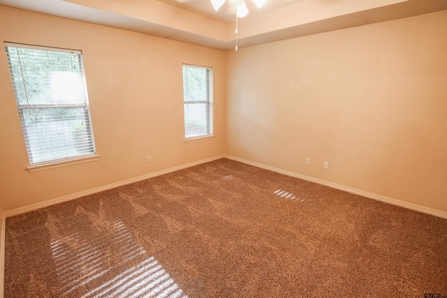 carpeted empty room featuring ceiling fan and a tray ceiling