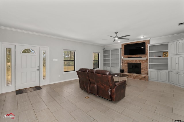 living room with built in features, a brick fireplace, ceiling fan, and crown molding