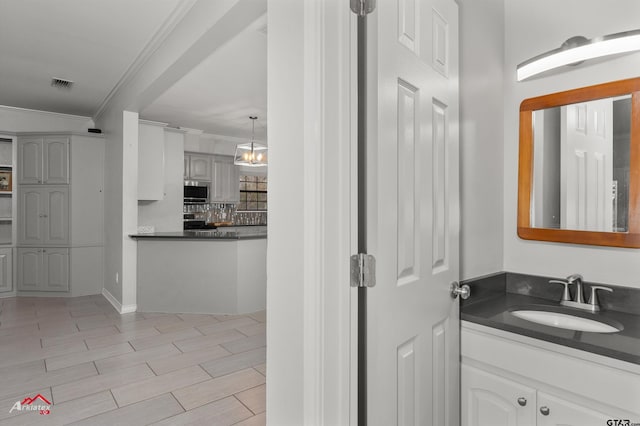 bathroom with tasteful backsplash, vanity, a chandelier, and ornamental molding