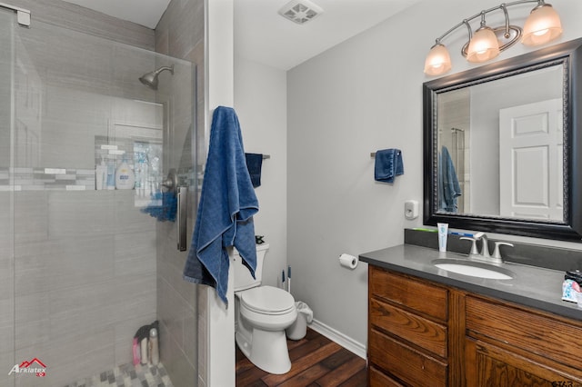 bathroom with hardwood / wood-style floors, vanity, toilet, and a tile shower