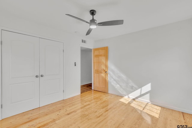 unfurnished bedroom featuring ceiling fan, light hardwood / wood-style floors, and a closet