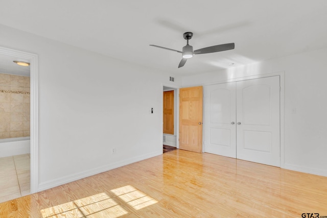 unfurnished bedroom with ensuite bath, a closet, ceiling fan, and hardwood / wood-style flooring