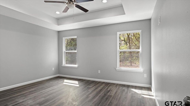 unfurnished room with a ceiling fan, baseboards, dark wood finished floors, recessed lighting, and a raised ceiling