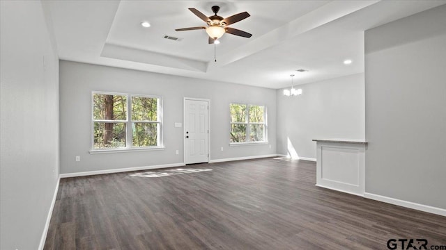 empty room with a tray ceiling, baseboards, visible vents, and dark wood-style flooring