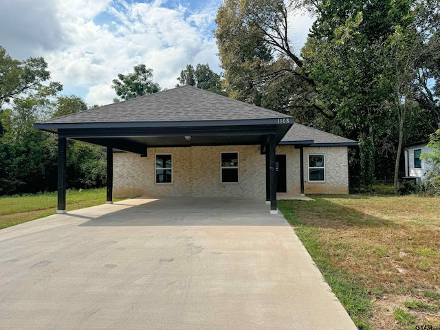 view of front of property with brick siding, a front lawn, roof with shingles, a carport, and driveway