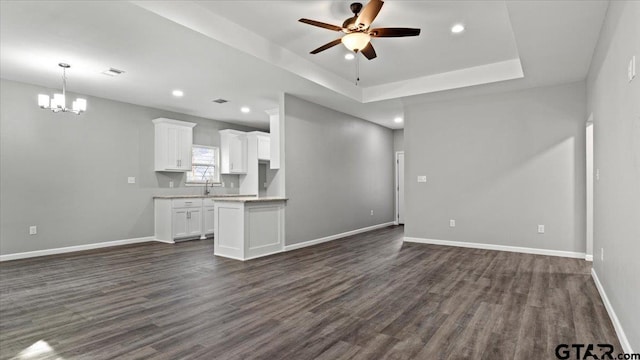 unfurnished living room featuring a raised ceiling, dark wood-type flooring, baseboards, and a sink