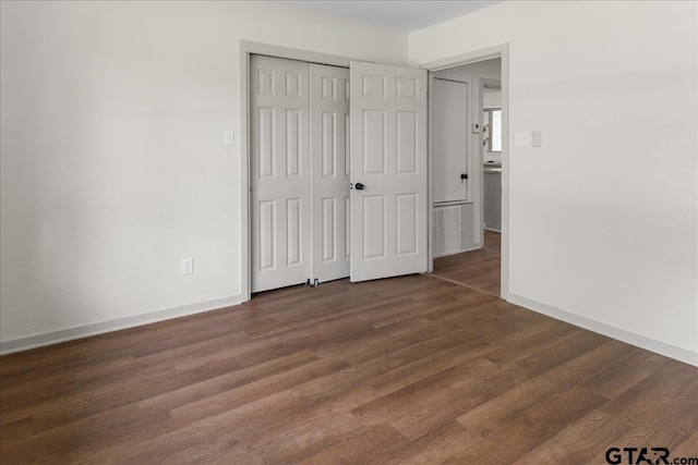 unfurnished bedroom featuring dark wood-type flooring and a closet