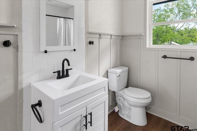 bathroom with hardwood / wood-style floors, backsplash, a shower with shower curtain, vanity, and toilet