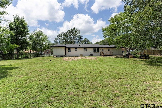 back of property with a wooden deck and a lawn