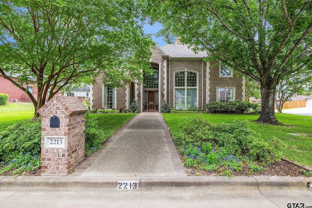2213 Woodlands Dr, Tyler, TX 75703 - view of front facade with a chimney, a front yard, and brick siding