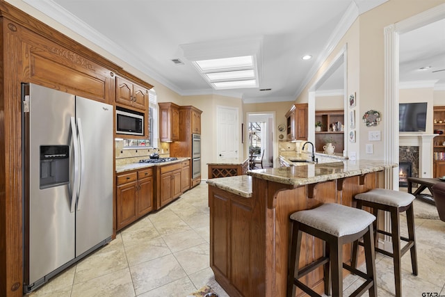 2213 Woodlands Dr, Tyler, TX 75703 - kitchen with stainless steel appliances, a sink, ornamental molding, tasteful backsplash, and brown cabinetry