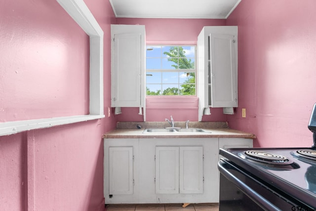 kitchen with white cabinetry, light countertops, black range with electric stovetop, and a sink