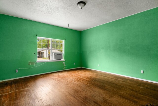 unfurnished room featuring baseboards, cooling unit, wood-type flooring, and a textured ceiling