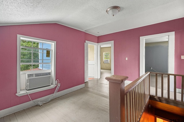 hall featuring vaulted ceiling, a textured ceiling, an upstairs landing, and wood finished floors