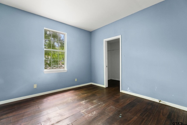 unfurnished room with baseboards and dark wood-style floors