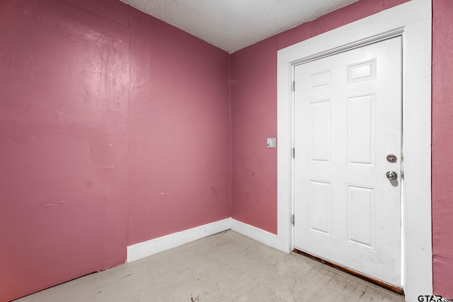 spare room with baseboards and a textured ceiling