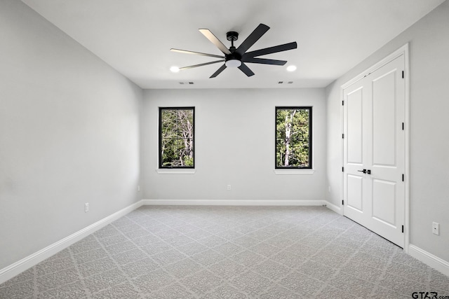 carpeted spare room with plenty of natural light and ceiling fan