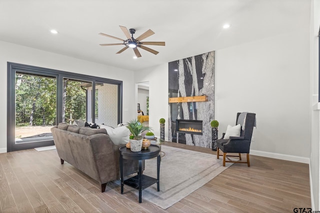 living room with a fireplace, light hardwood / wood-style floors, and ceiling fan