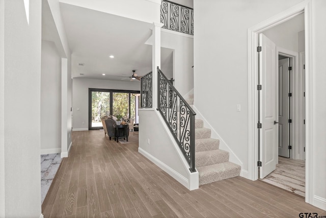 staircase featuring wood-type flooring and ceiling fan