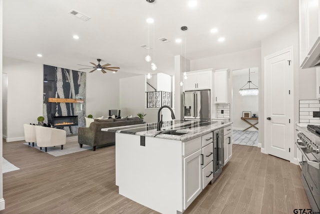 kitchen with white cabinetry, sink, a center island with sink, and stainless steel appliances