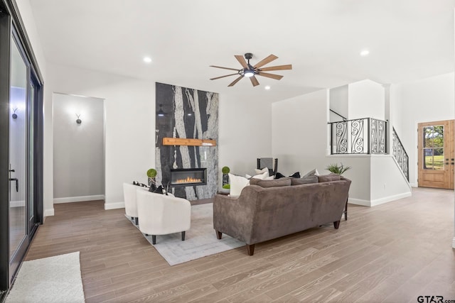 living room featuring a high end fireplace, ceiling fan, and light hardwood / wood-style flooring