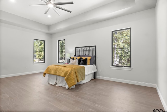 bedroom featuring multiple windows, ceiling fan, and light hardwood / wood-style flooring