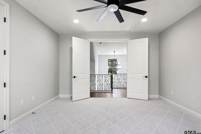 unfurnished bedroom with ceiling fan with notable chandelier and light carpet