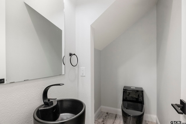 bathroom with sink, hardwood / wood-style flooring, and vaulted ceiling