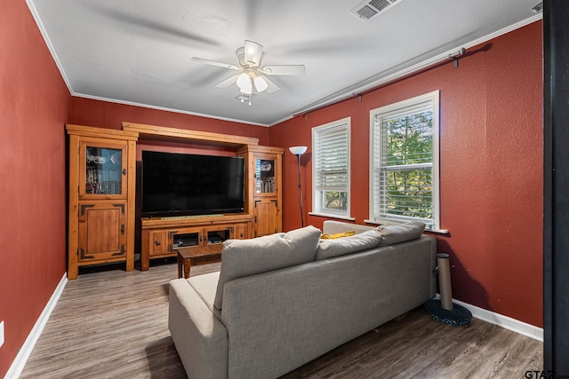 living room featuring hardwood / wood-style floors, ceiling fan, and crown molding