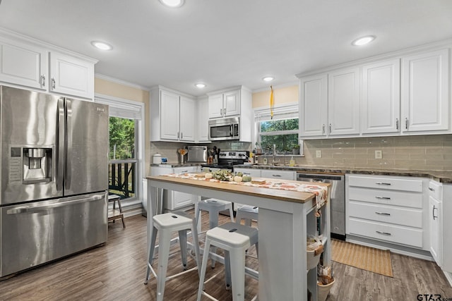 kitchen with stainless steel appliances, a wealth of natural light, white cabinets, and dark hardwood / wood-style flooring